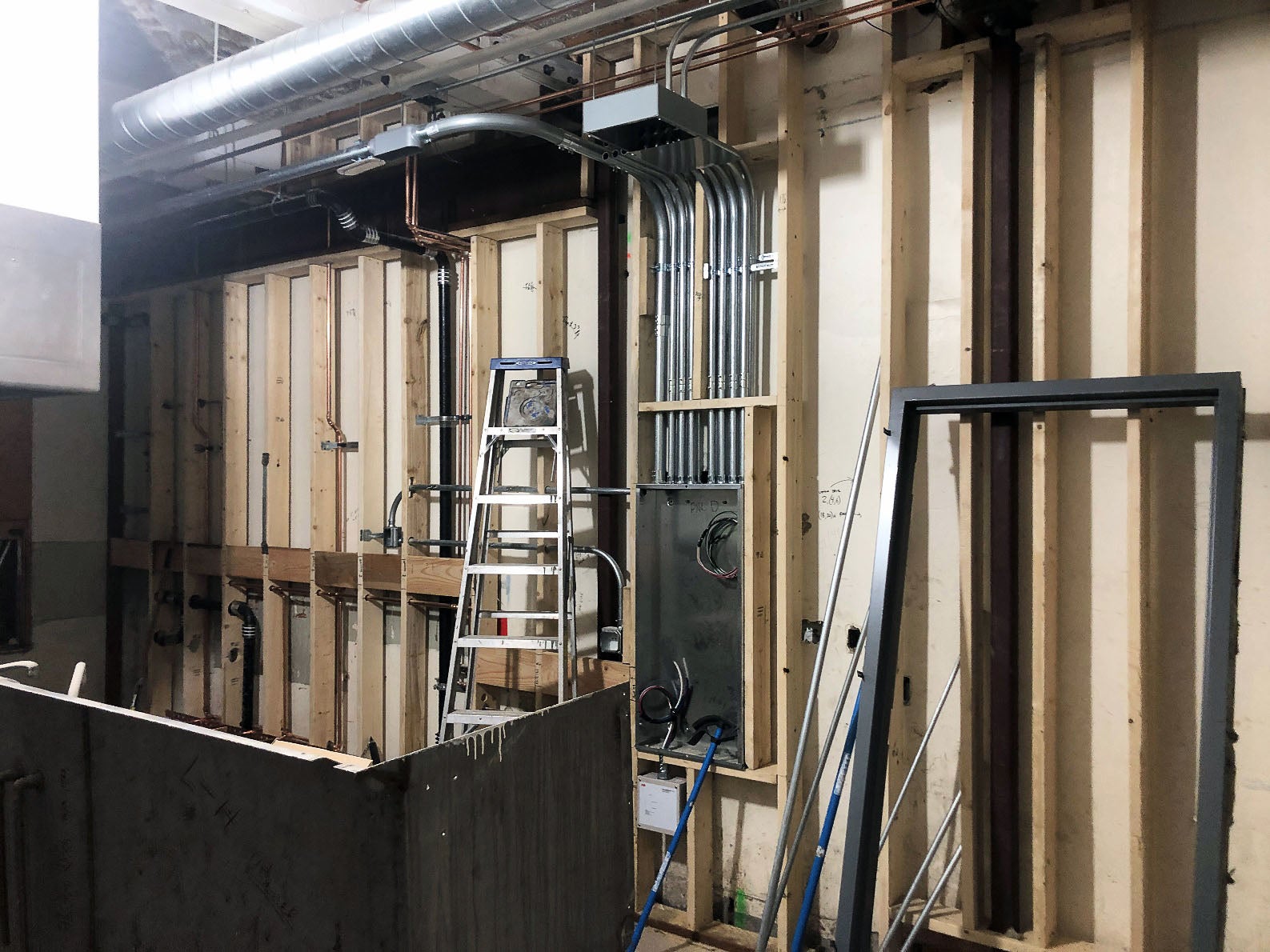 wood framing is open to the room with wallboard on the back side of it. piping, ducts, and electrical conduit can be seen in the walls