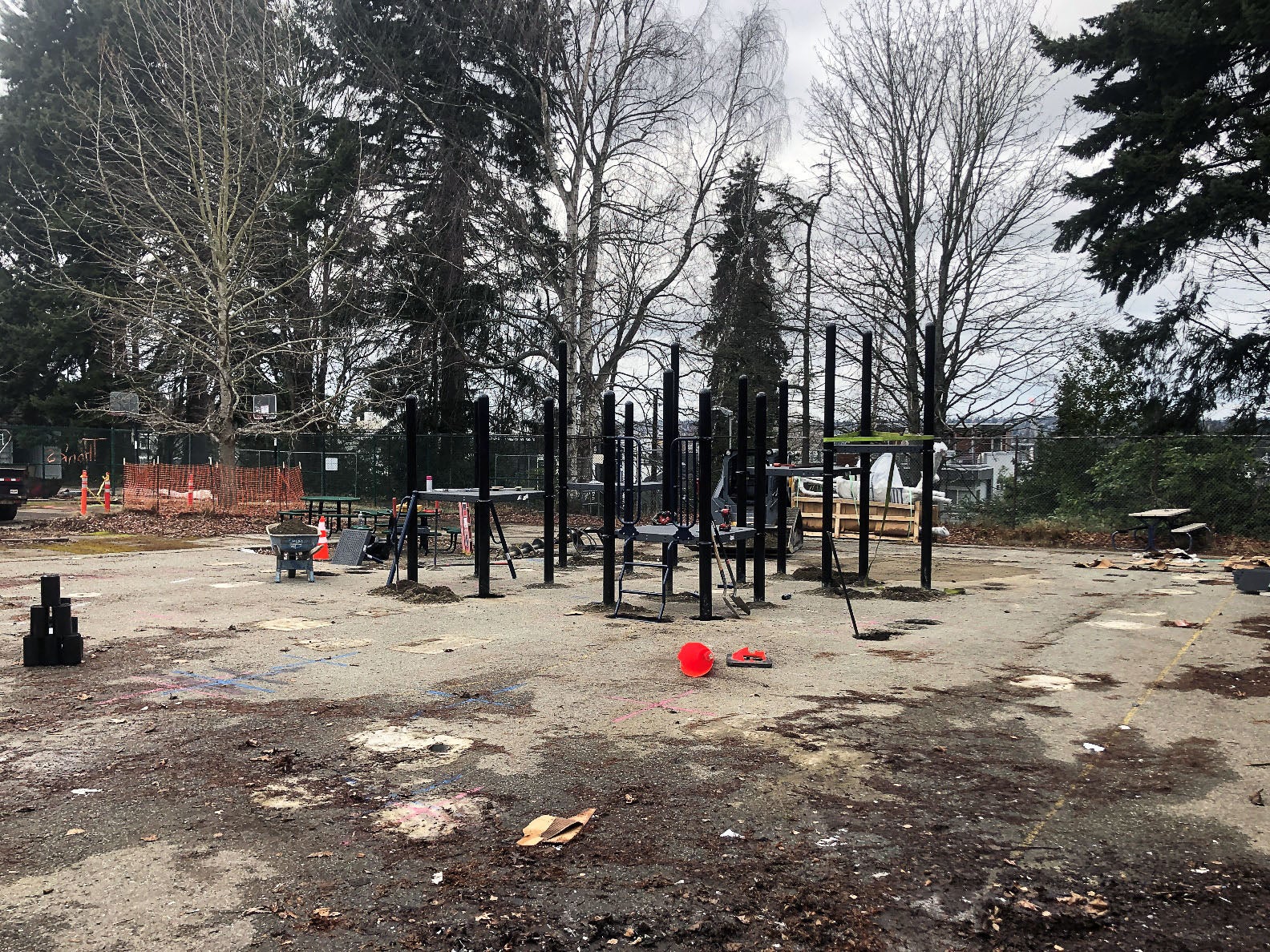 a concrete pad has part of a play structure installed. trees are in the background