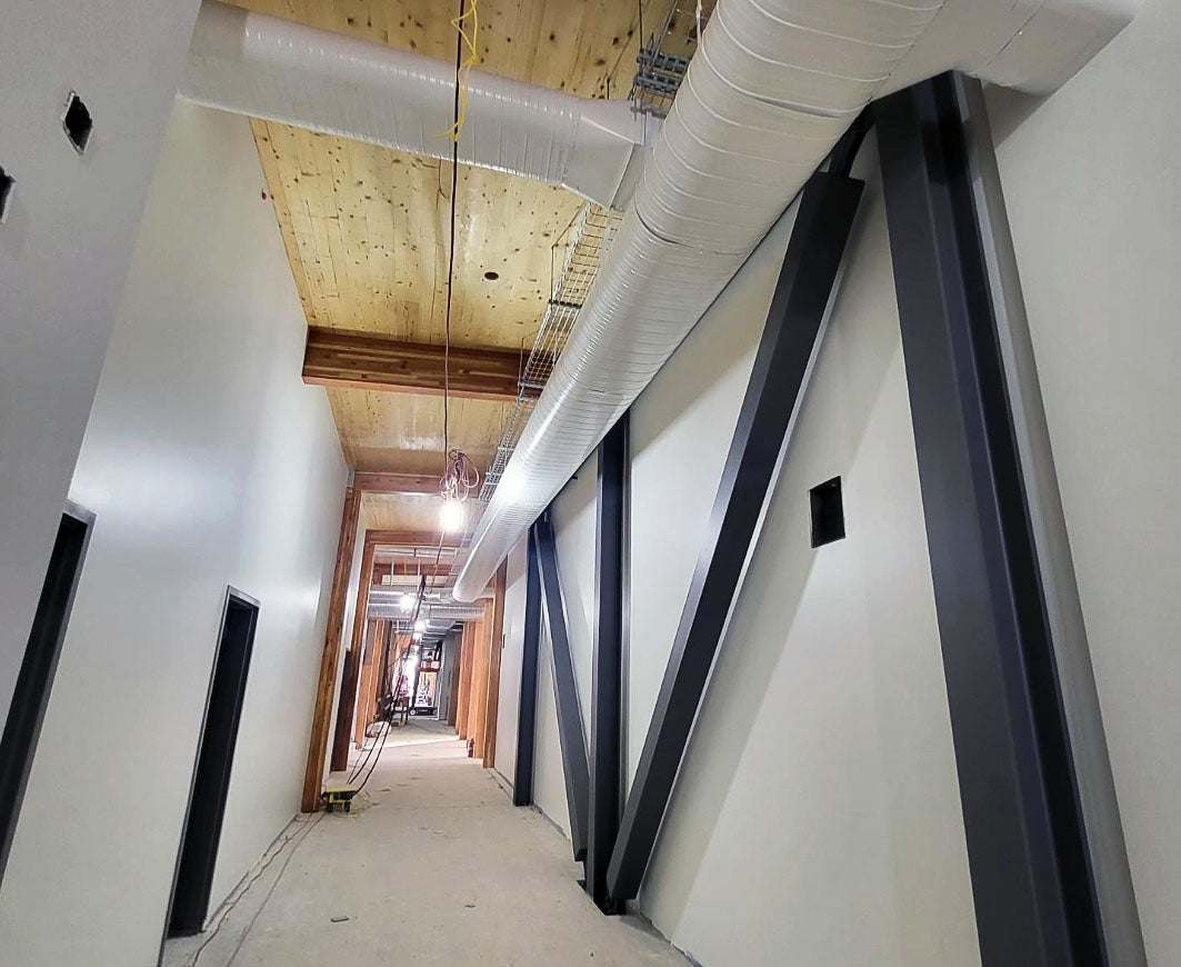 a long hallway with steel bracing and a wood ceiling