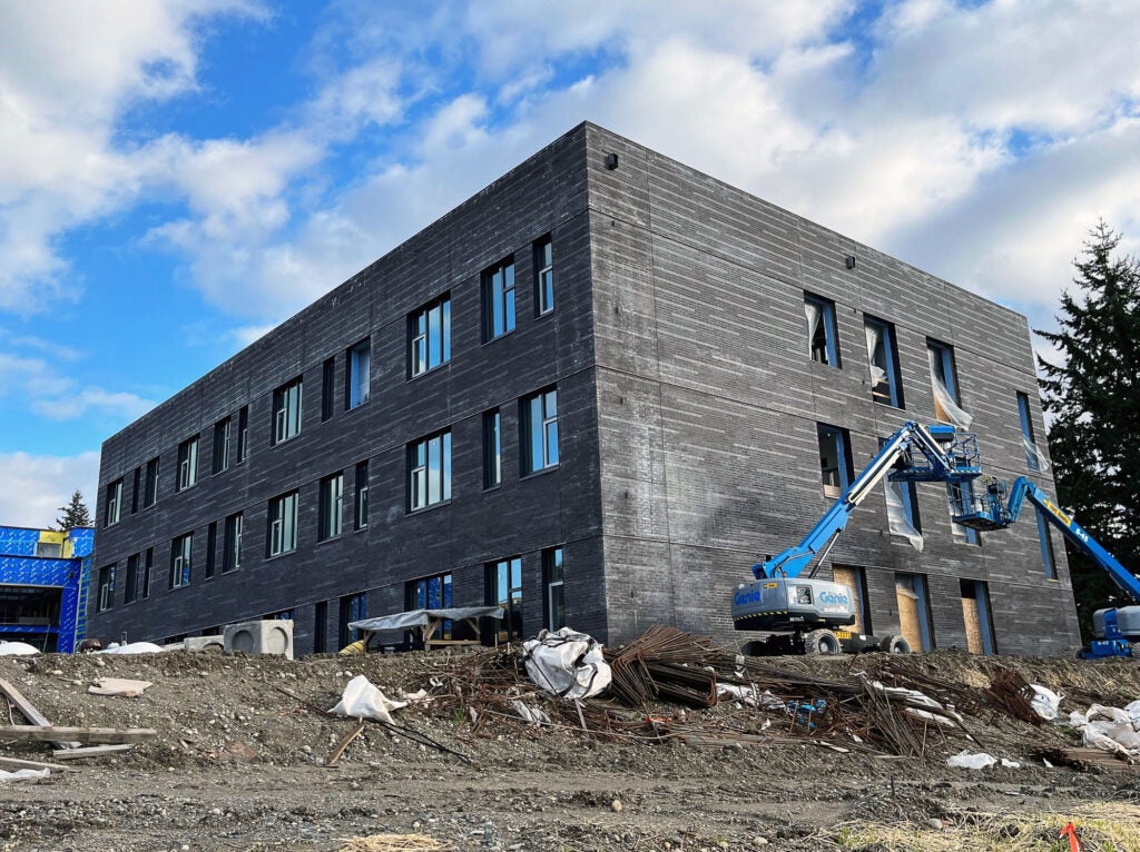 3-story gray brick covered building with a lift by one window