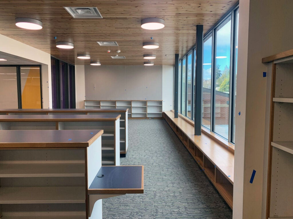 an empty library with shelves, windows, and a bench under the windows