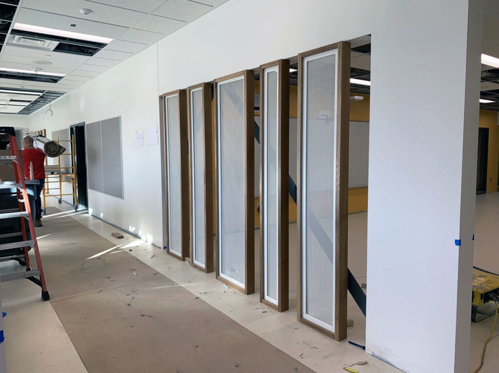 a hallway with a tackboard and framed screens separating it from another area