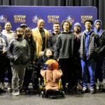 A group of Rainier Beach students and Warren Moon pose for a photo on a school stage
