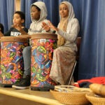 A group of students play the drum on a stage