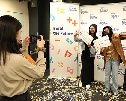 Two students pose for a photo while another takes a photo.