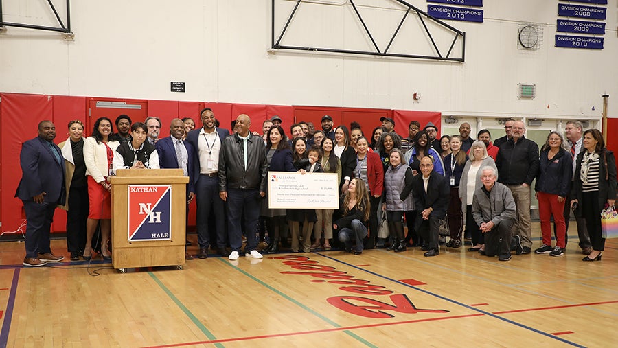 A group of people stand together in a school gym with Principal Jackson