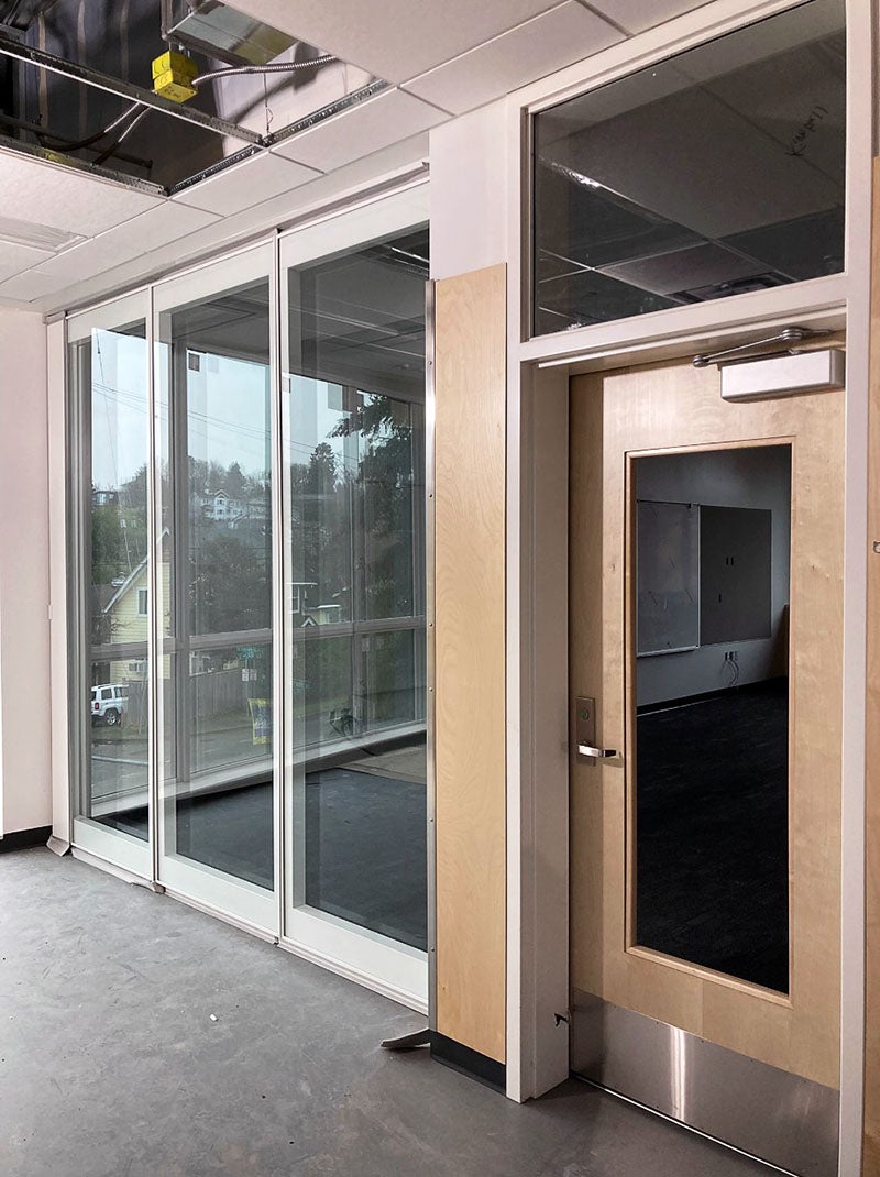 Three panels of tall windows reach all the way to the floor with a door in the wall next to them