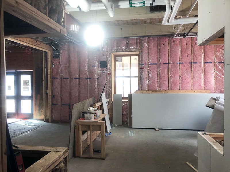 a room under construction has pink fluffy material between wall studs, a window to outside, and a partially built large box