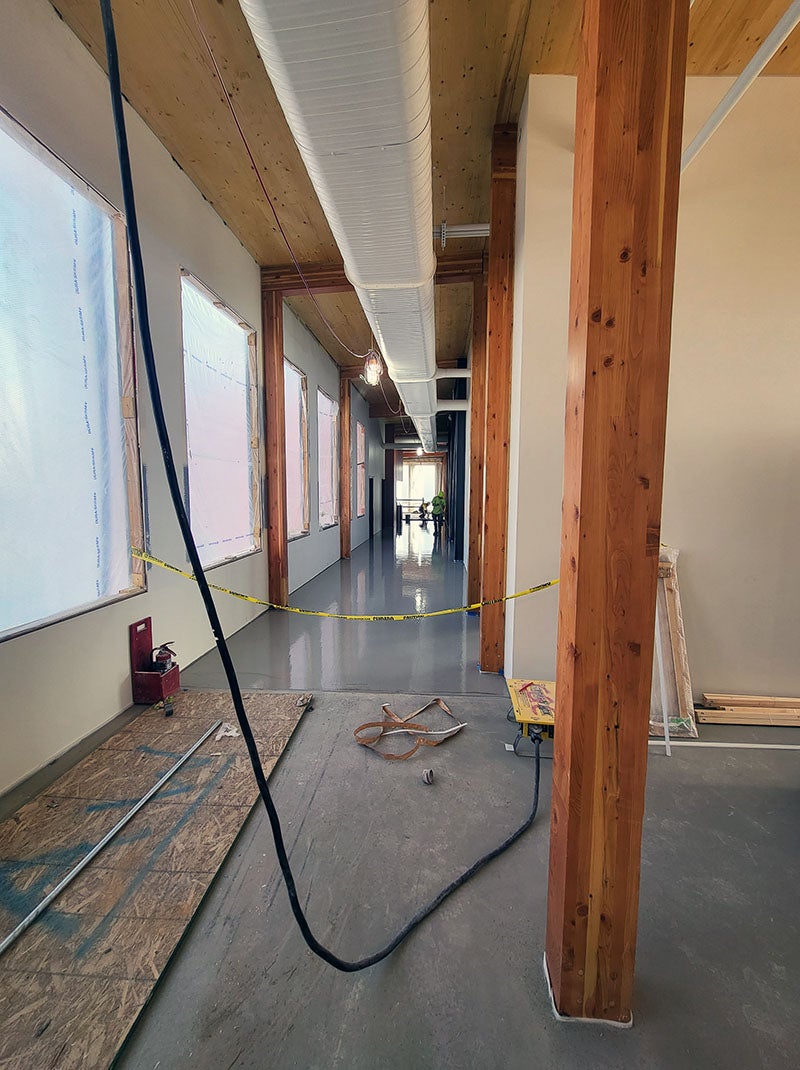 a shiny concrete floor in a hallway that is taped off with construction tape