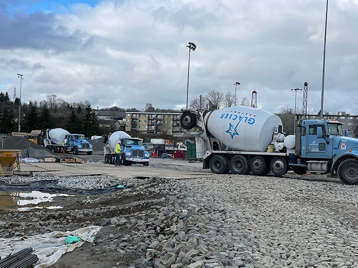 concrete mixer trucks lined up on a drive way among mud puddles