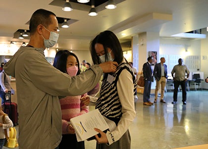 a parent helps a student get ready for the awards ceremony