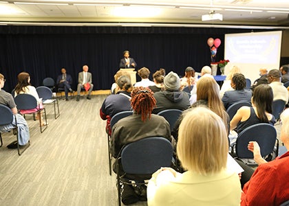 A group listens during the awards ceremony to a speaker at a podium