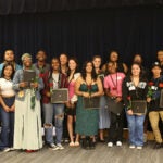 A large group of students gather for a photo in the auditorium