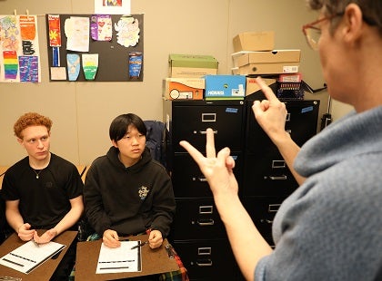 Two students watch their teacher provides a sign