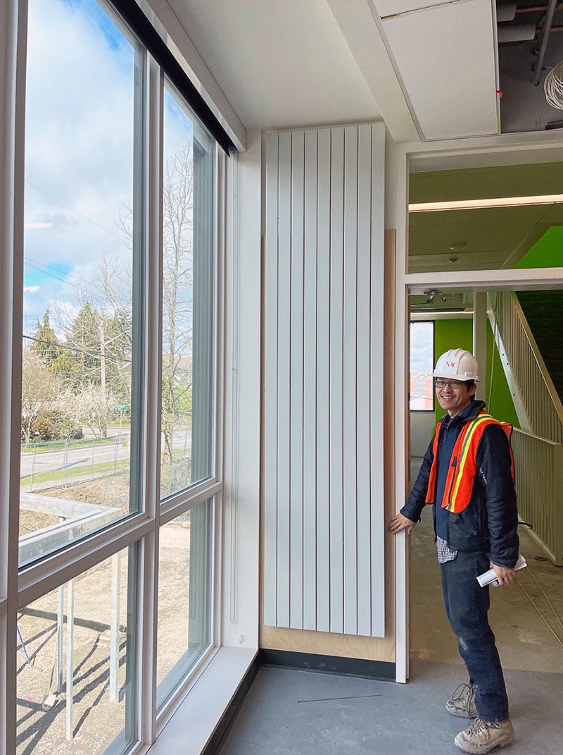a person stands by a striped panel on the wall next to a window