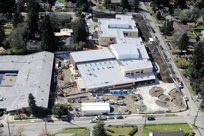 aerial view of a large building with a new roof and a large building with an old roof - there is construction equipment between them