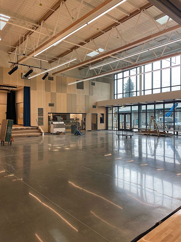 a large room with two story ceilings a wall of windows and a polished concrete floor
