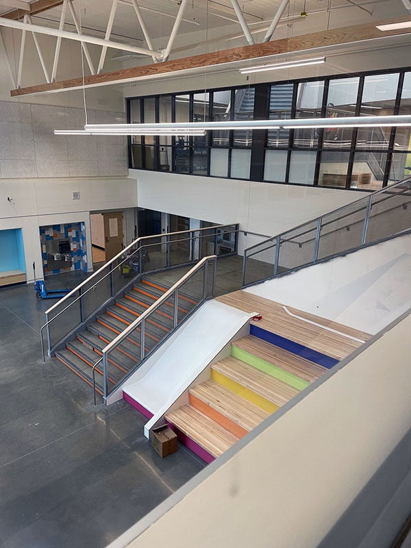 looking down into a large space with a stairway for walking, a stairway for sitting, and a slide