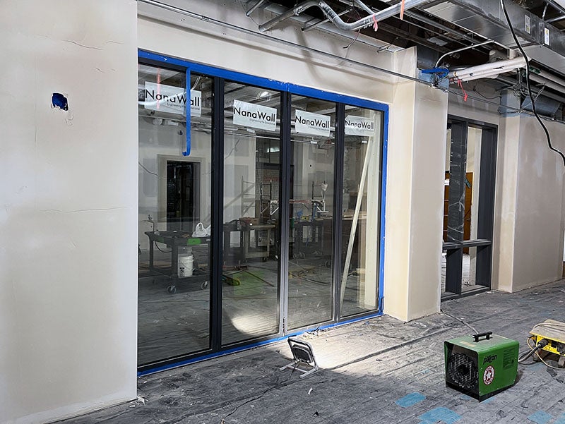 an unfinished gypsum covered wall has a four-panel glass door installed