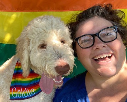 Rachel Barrett smiling at camera next to her dog, Goldie.