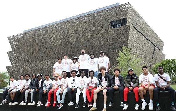 A group of students pose for a photo in front of the National Museum of African American History and Culture