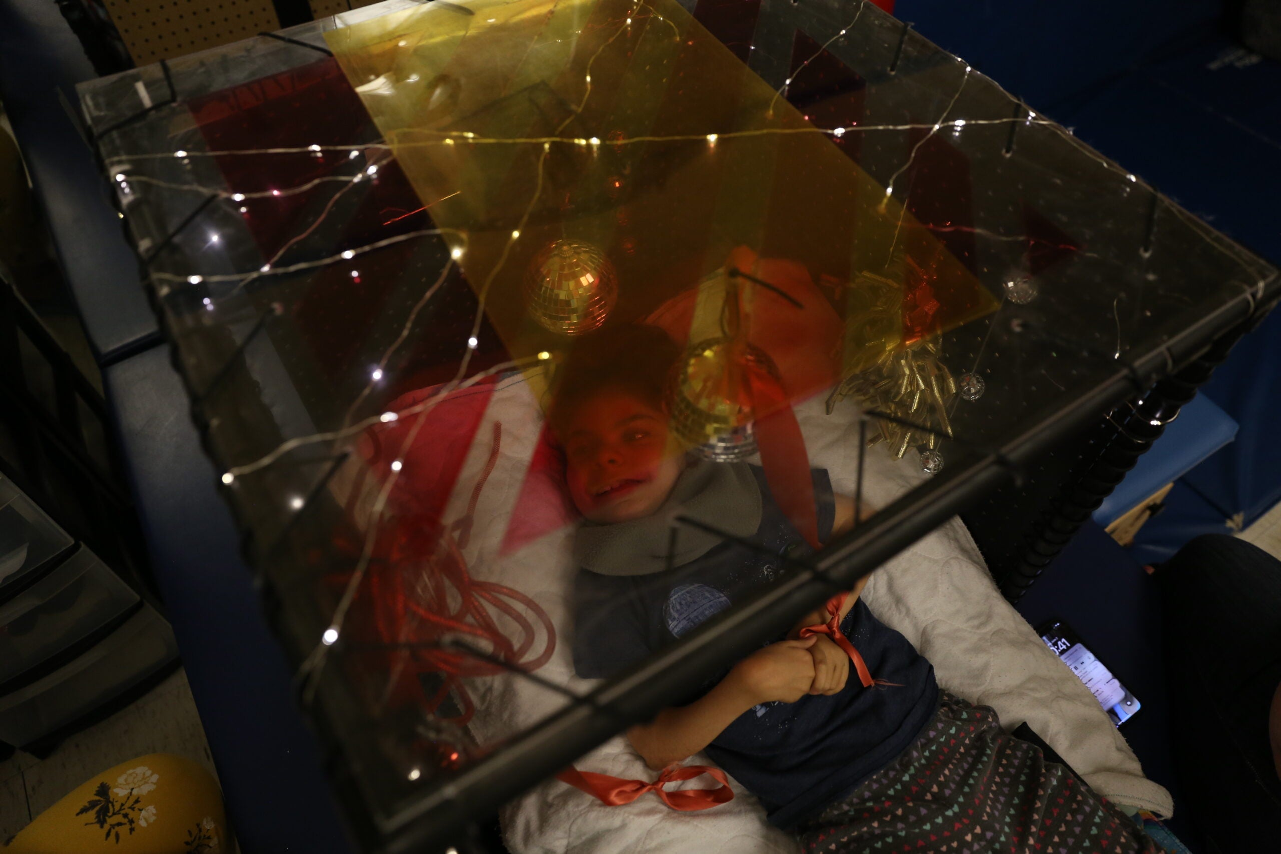 Student laying in tiny room looks up at lights and disco balls.