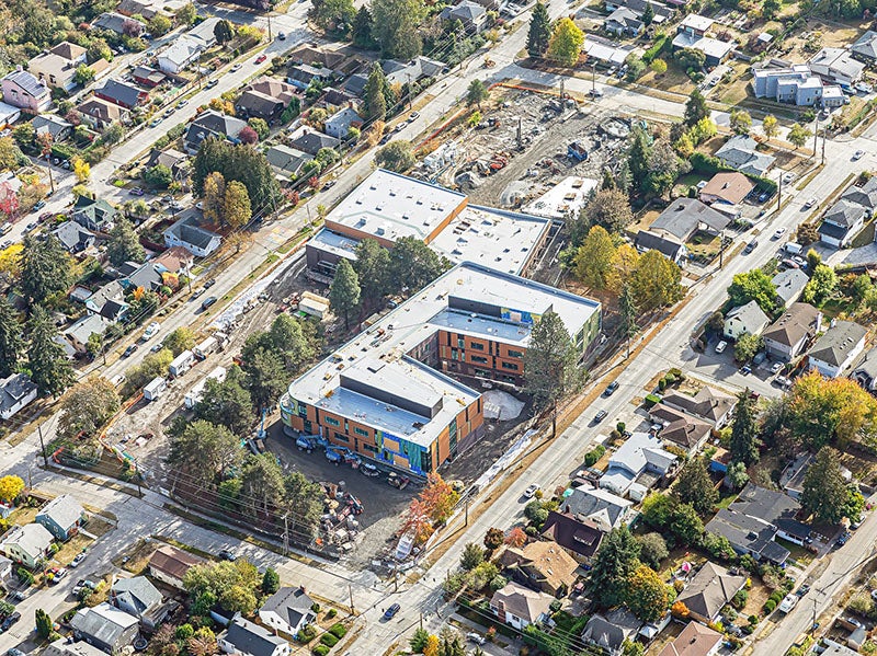 aerial of two connected large buildings with construction on site. houses are all around across the street