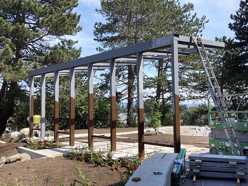 a metal frame of posts and rafters forms the frame of a structure with paving underneath