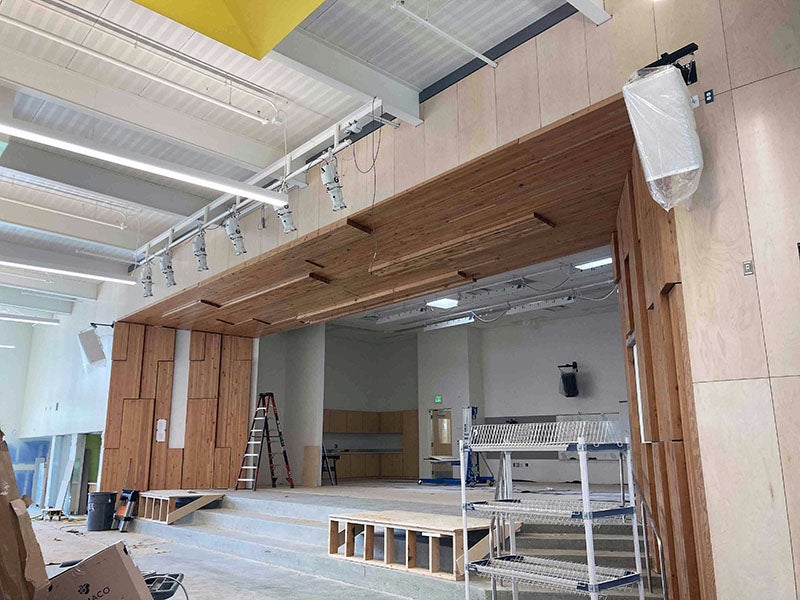 a stage proscenium over a raised stage has wood panels partially installed