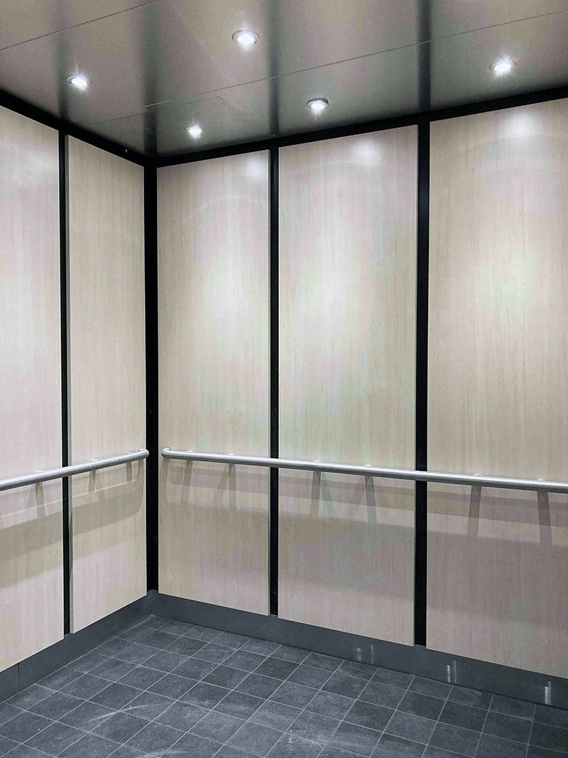 the inside of an elevator has squares on the floor and a railing around the walls