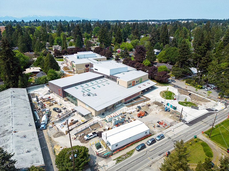 aerial view of a large building with construction and a concrete truck on the lower part of the site