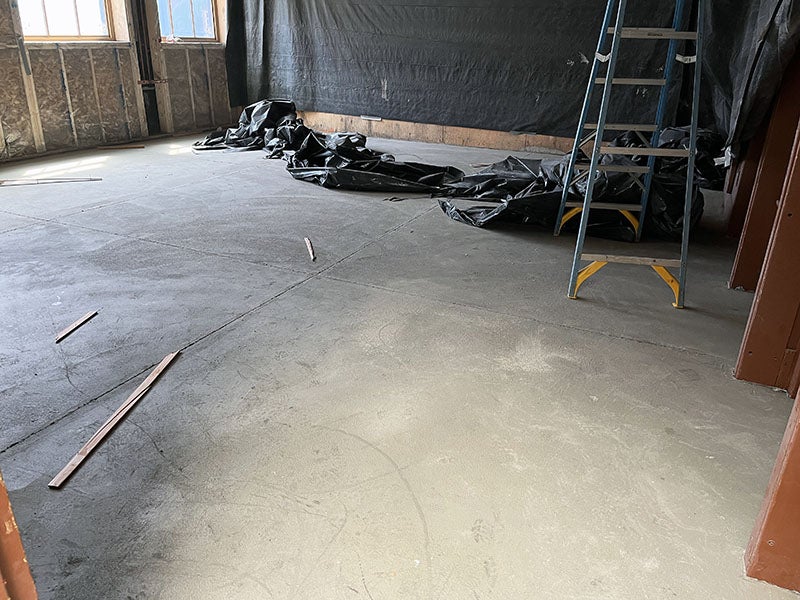 a smooth concrete floor with a wall that has studs and windows