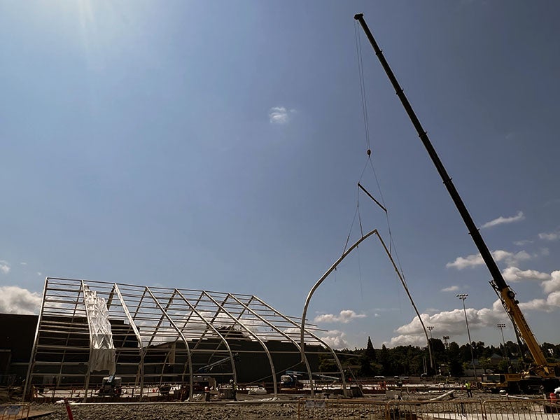 a crane is lifting a large frame piece from a structure of pipes