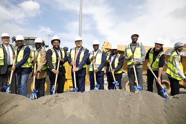 Superintendent Brent Jones, Seattle Mayor Bruce Harrell, and various SPS leaders in construction vests and hard hats holding shovels to break ground at Rainier Beach