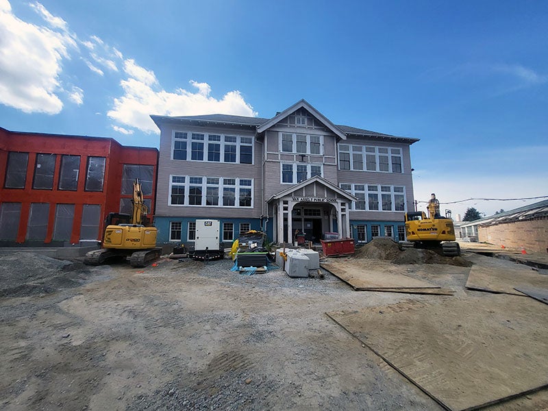 A three story building with a peaked roof over the entry has windows on all levels