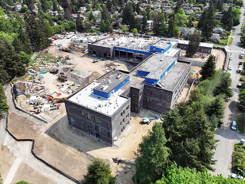 aerial of a large L shaped building with dirt and construction equipment around it