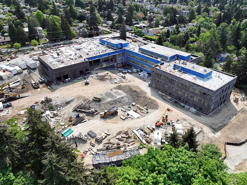 aerial of a large L shaped building with the lower right part three stories