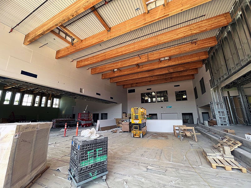 a two story room with wood beams on the ceiling and a raised concrete stage and steps to the right