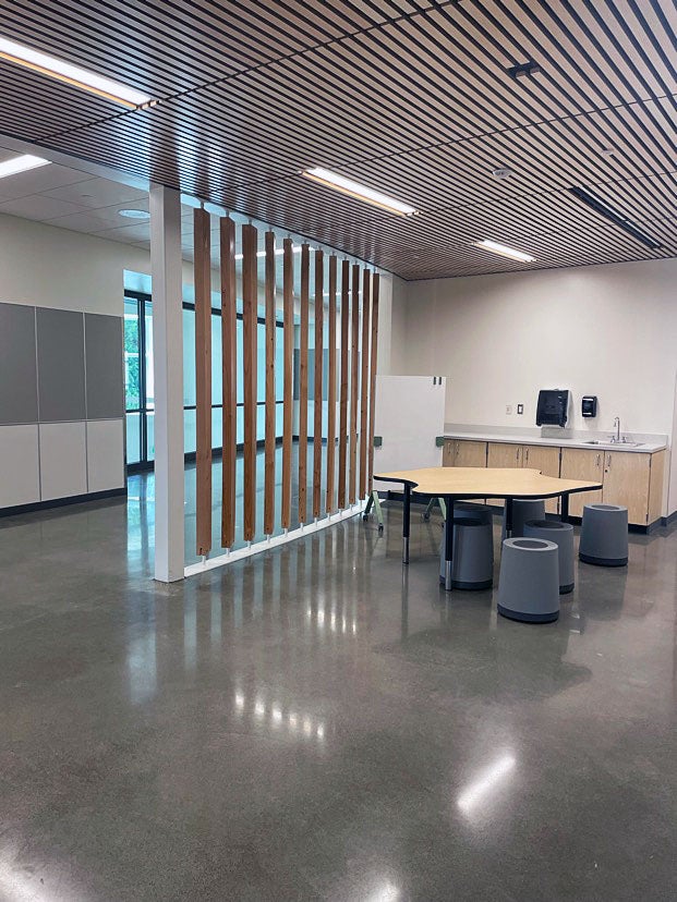 indoor space with a slated ceiling, a table, stools, and a counter and sink. it is separated from the hall by a partial wall