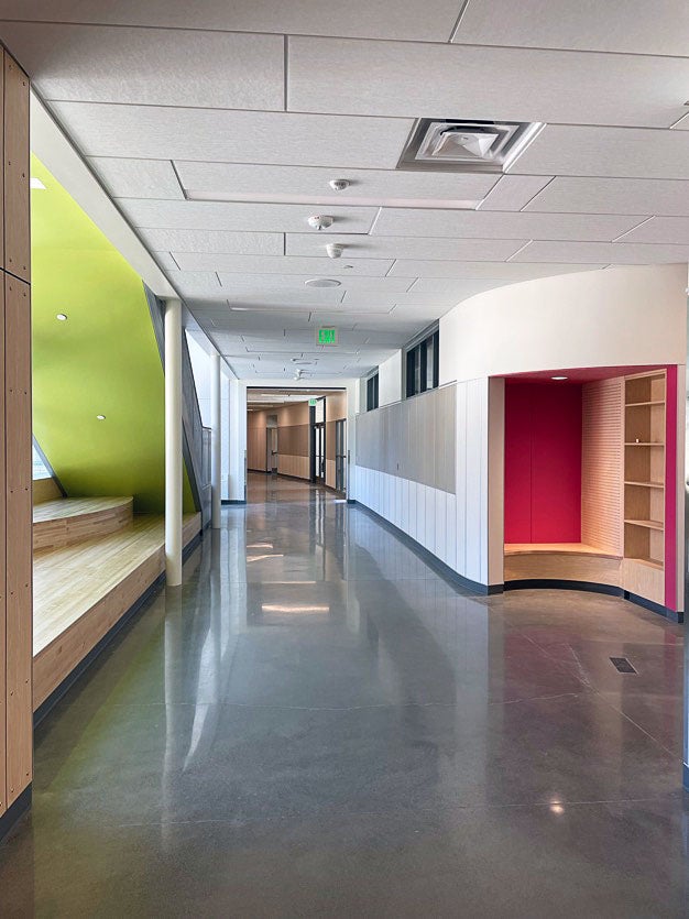 part of a hallway with wood benches on one side by the windows and a curved nook on the other side