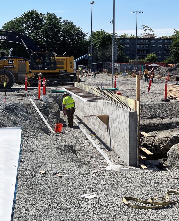 an outdoor construction area with gravel and a concrete wall