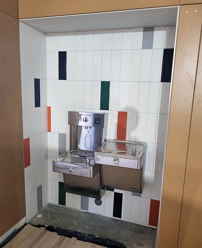 an alcove has tile walls, a drinking fountain, and a water bottle filling station