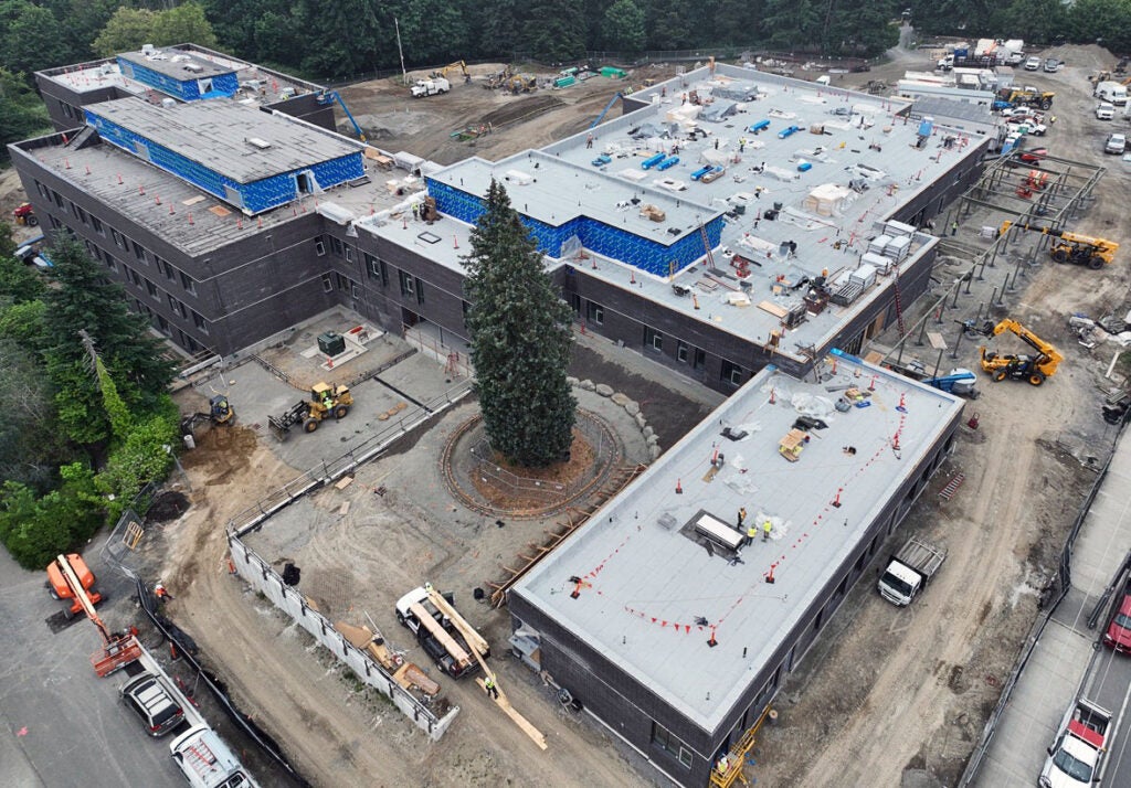 aerial of a large building with roofing work, and construction machines around it