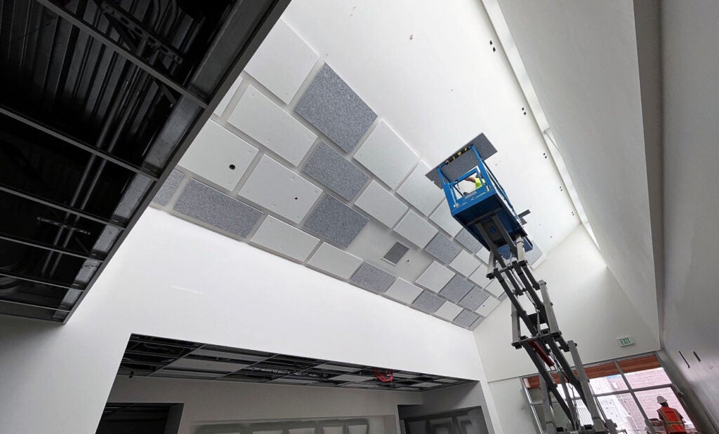 a person on a jacklift is installing ceiling tiles on an angled ceiling