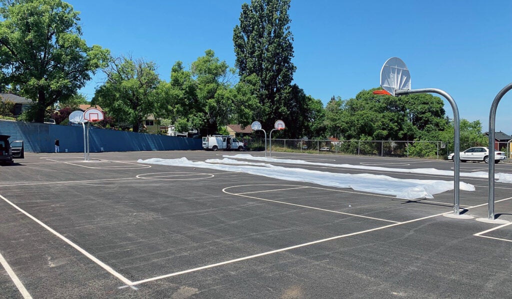 two basketball courts have striping and hoops