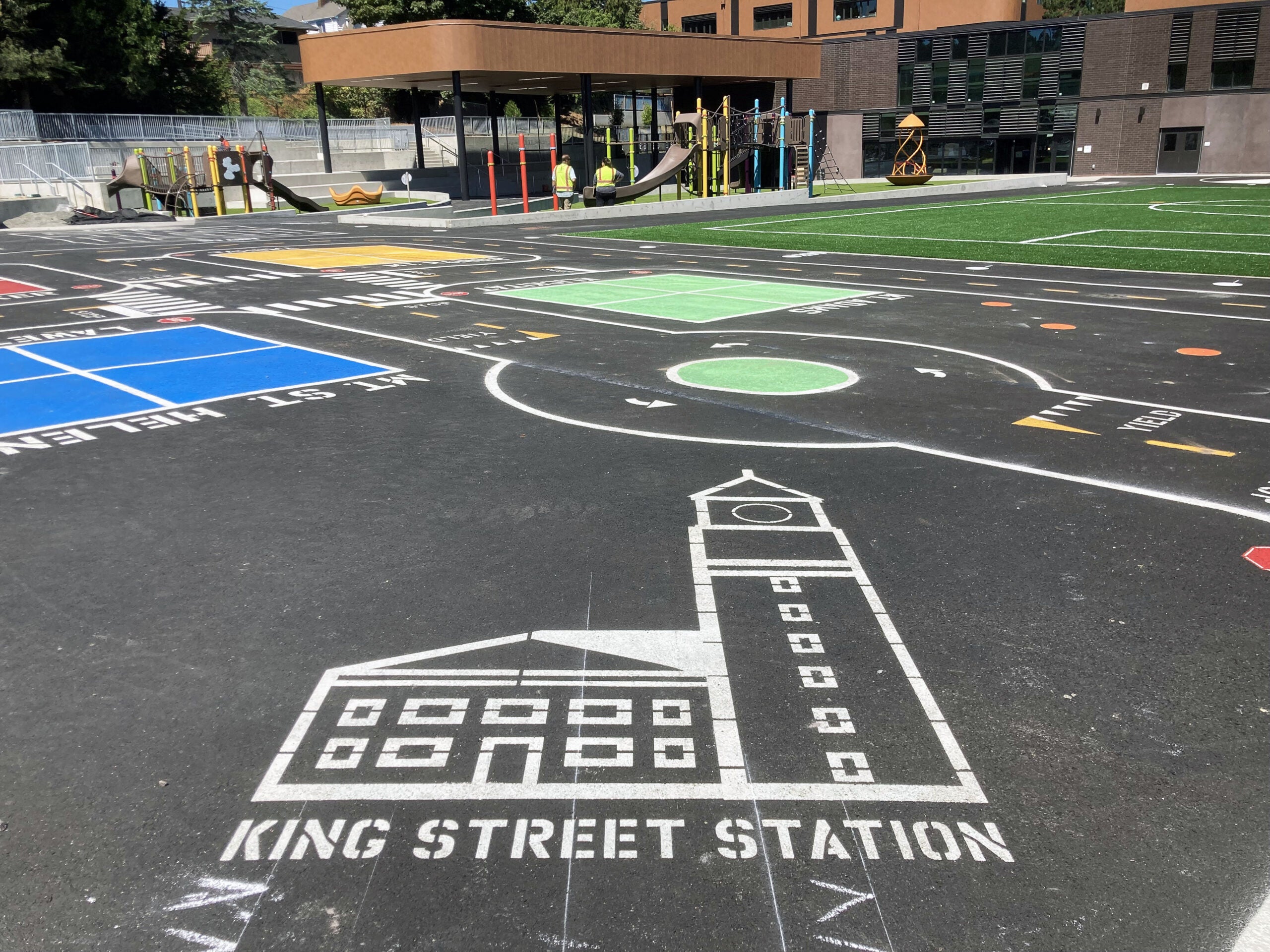 a paved area in front of a building has road lines and building outlines painted on it