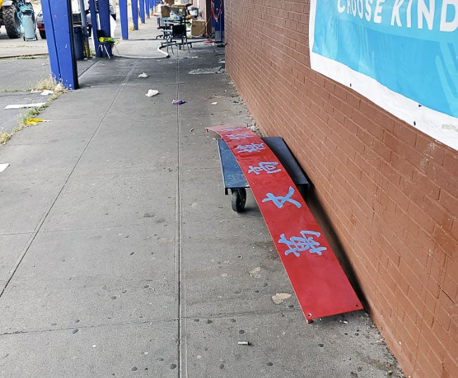 a brick wall has a long red strip of metal with characters from an Asian language on it in blue