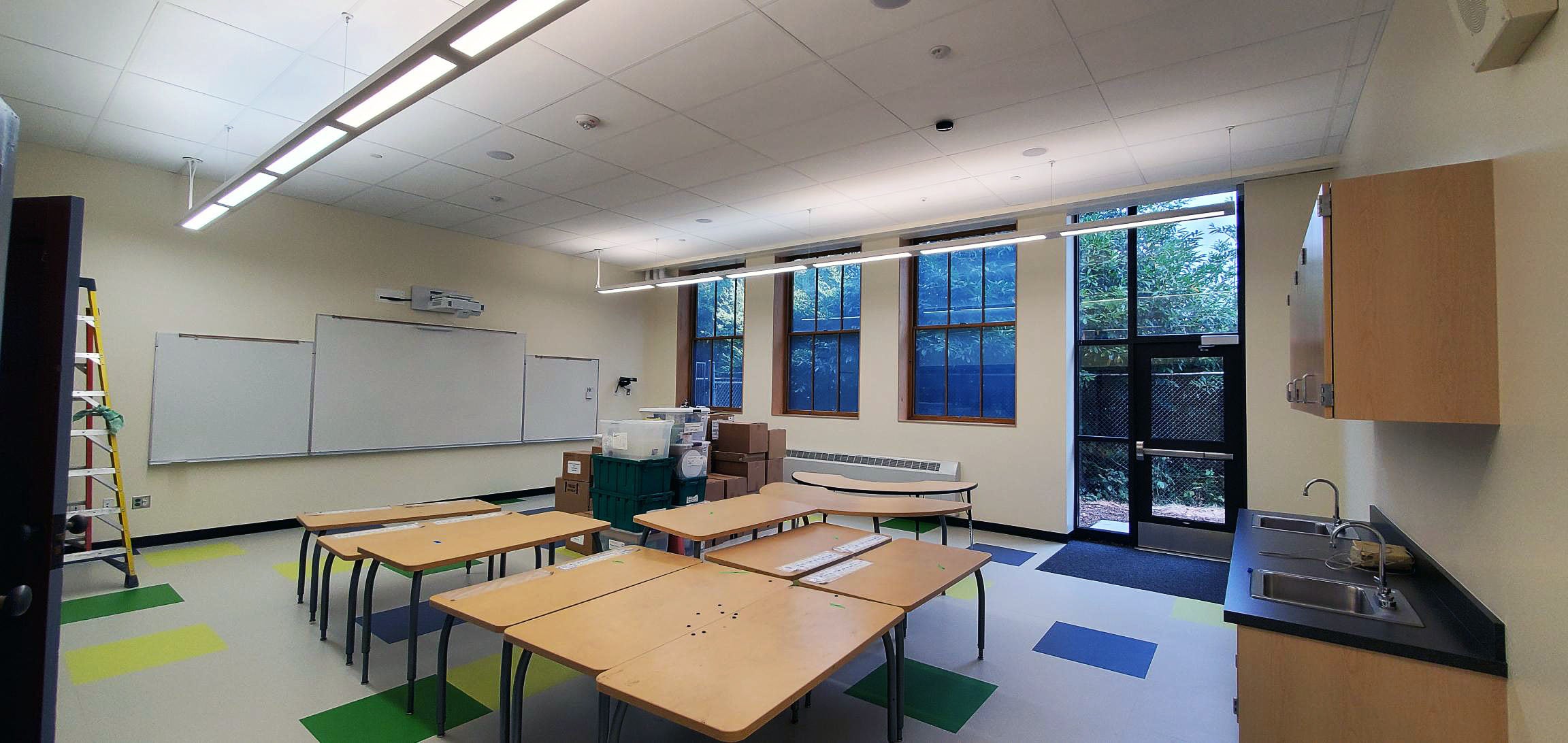 a classroom with a door leading outside and windows on one wall