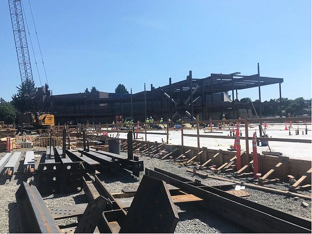 a steel frame is being built on top of a concrete floor. a crane is on the left side