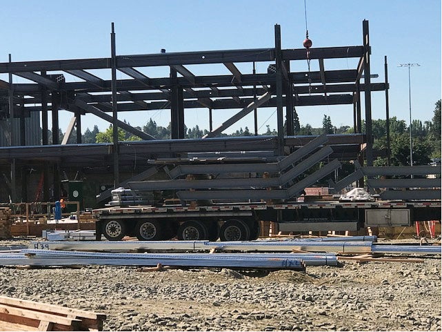 a steel frame has a large delivery trailer in front of it with bent steel on it